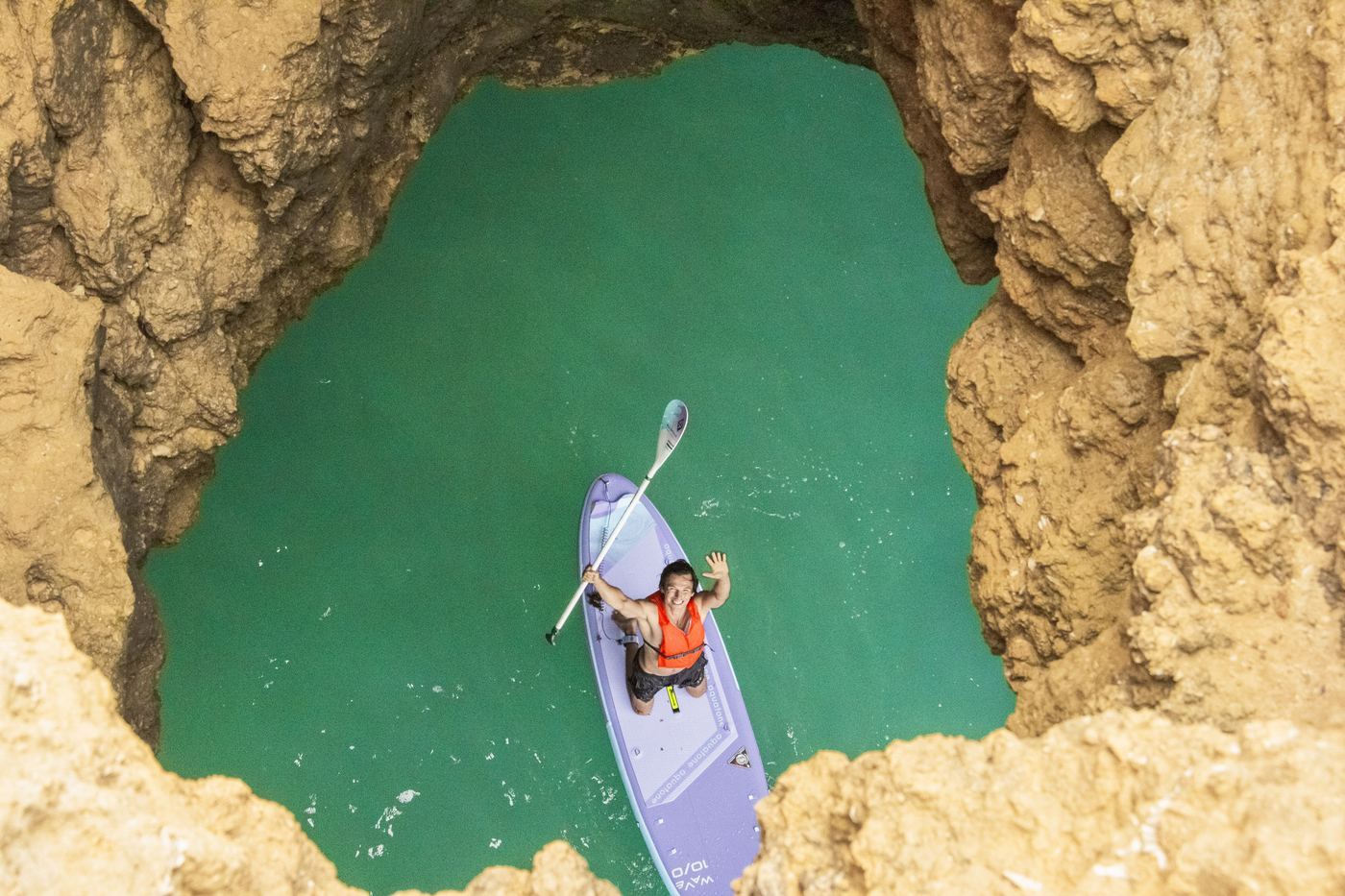 Paddler waving inside Algarve sea cave