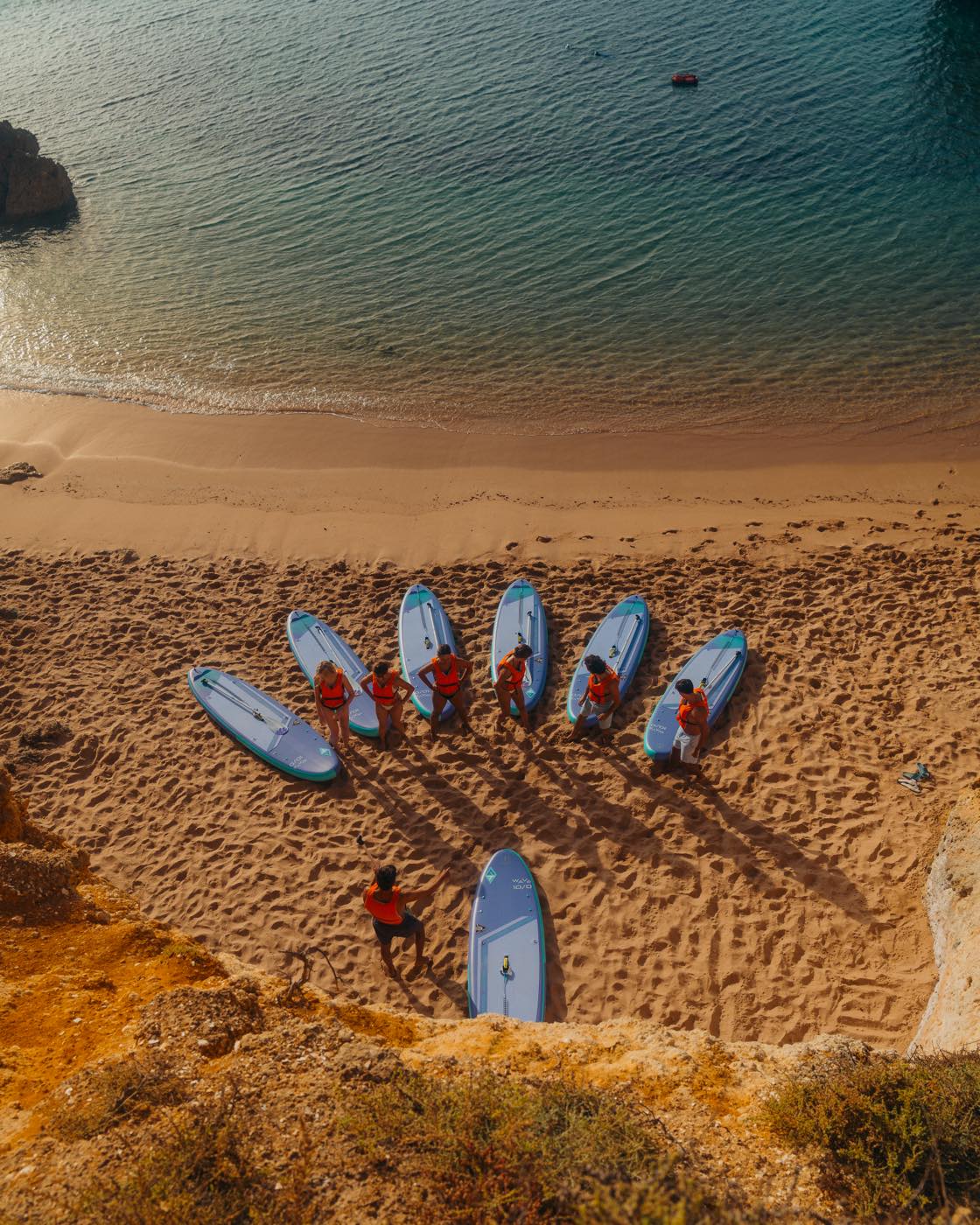 Group of paddlers lined up on the beach at golden hour