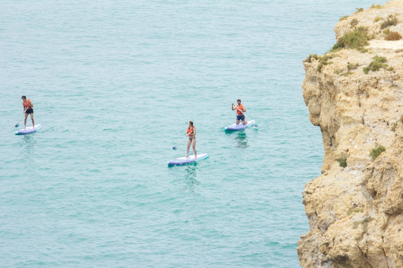 Three paddlers near Algarve cliff