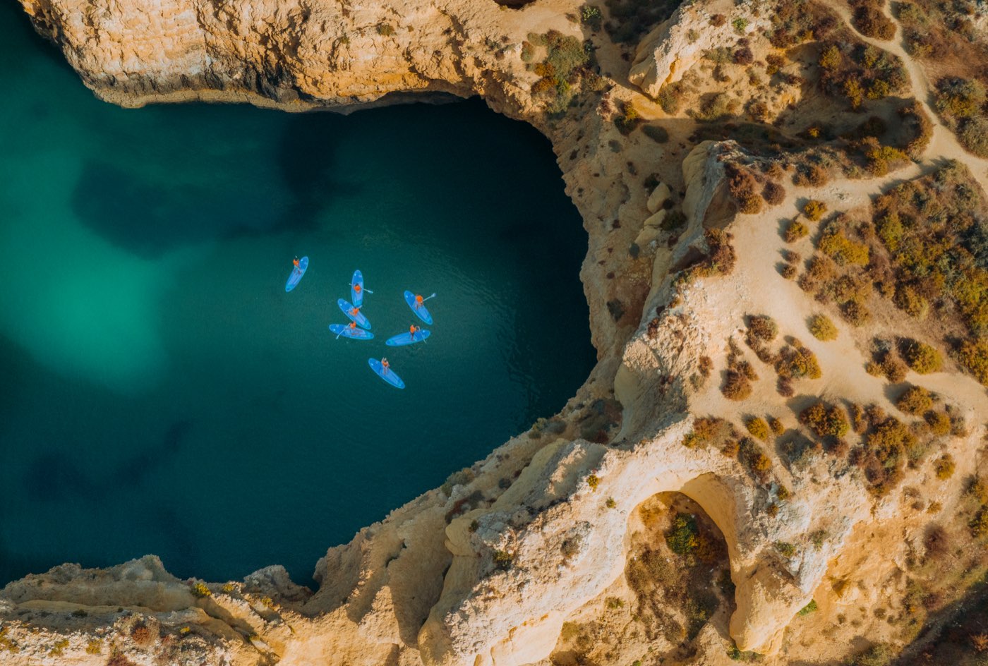 Aerial view of paddlers in a turquoise Algarve cove