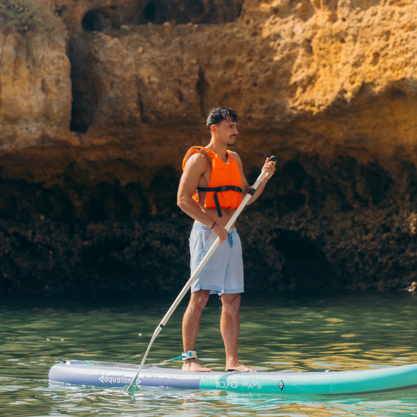 Paddler in orange life vest inside an Algarve sea cave